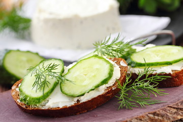 Sandwiches with soft cheese, cucumbers and greens
