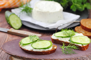 Sandwiches with soft cheese, cucumbers and greens