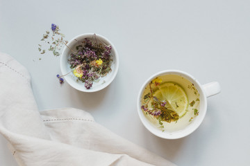 Tea time. Cup of hot herbal tea and dry tea on the gray background, top view