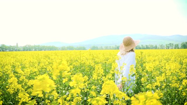 Frau mit Hut in gelb blühendem Rapsfeld im Sommer