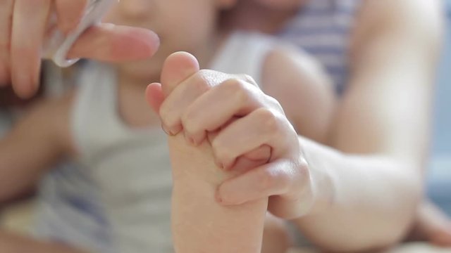Mom cut off the baby's nails on the legs close-up from the child.