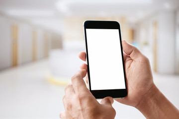 Man using Smartphone with Blurred Hospital Counter background. Blank screen For Graphic display montage.