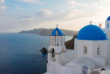 traditional greek village Oia of Santorini, with blue domes of churches in sunset light, Greece