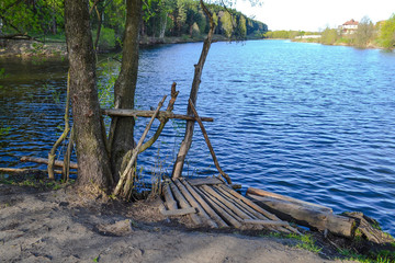 Fototapeta na wymiar Homemade pier for fishermen from the thick branches on the lake.
