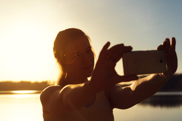 Happy caucasian woman making selfie at sunset
