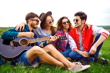 Obraz premium Group of friends enjoying party. The guy plays the guitar. Everyone has a great mood. Summer time.