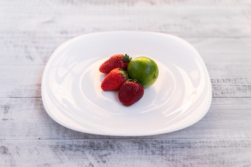 Lime and strawberry on a wooden table