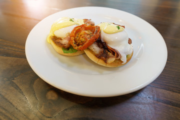 Delicious Eggs Benedict served on white plate on wood table