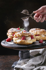 Homemade choux pastry cake Paris Brest with raspberries, almond and rosemary, served on black...