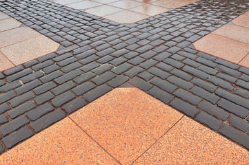 Covering pavement of black gravel and red granite slabs.
