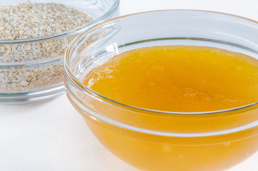 Oat bran and honey in a glass bowl isolated on white background. Closeup shot. Healthy food concept.