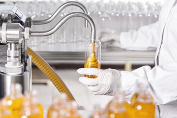 Production process of cosmetics in laboratory. Laboratory scientist dressed in hospital gown and...