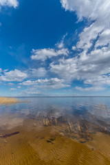 Sunny view on blue calm lake. Nature landscape. Massive clouds.