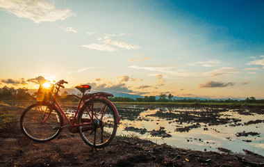 Fototapeta premium Beautiful landscape with red classic bicycle against sunset sky background