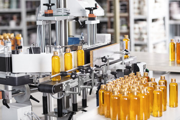 Cosmetics factory. Bottling line filled with yellow shampoo. Automated process on factory. Line of...