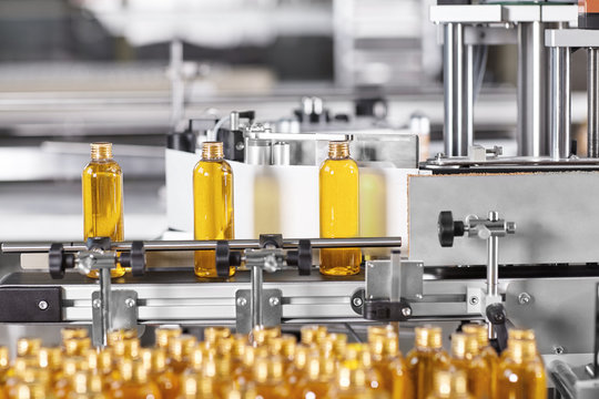 Factory process of production new cosmetics. Glass bottles standing on conveyor line going to be twisted. Automated process on big factory. Production of new shampoo on coveyor belt.Innovation concept