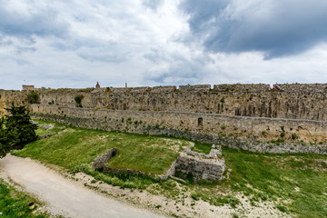 Fototapeta premium Medieval walls of Rhodes and moat under moody cloudy sky, Rhodes island, Greece