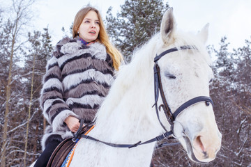 Nice girl and white horse in a forest in a winter