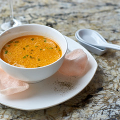 Creamy crab soup served with crab chips and glass of white wine on marble backround