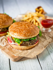 Tasty american hamburger with beef, sauce and french fries on rustic table. Flat lay. Top view. © artifirsov