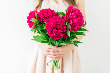 Young woman holding in hands bouquet of peonies. Woman in pink dress. Sweet romantic moment