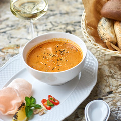 Peranakan cuisine. Singapore Laksa soup served with glass of white wine, bread, ceramic spoon, crab chips, slice of lemon and fresh vegetables on marble table