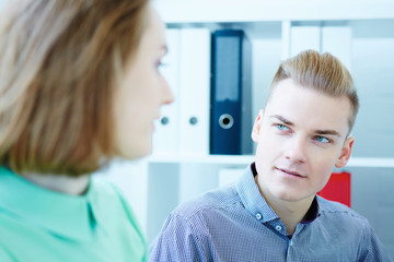 Two young coworkers working together in a modern coworking studio. Business partners using laptop and discussing new startup project.