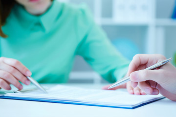 Young female employee of the staffing agency helps fill out the form to the male job seeker....