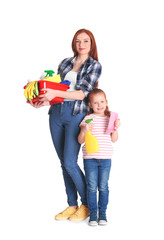 Little girl and her mother with cleaning supplies on white background