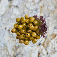 Appetizer. Green olives served in martini glass on marble table. Top view or flat lay.