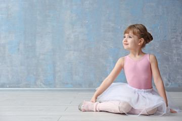 Cute little ballerina sitting on floor in dance studio - obrazy, fototapety, plakaty