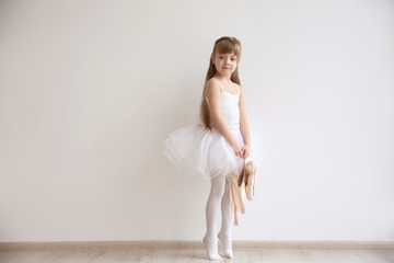 Beautiful little ballerina holding ballet shoes in light dance studio © Africa Studio