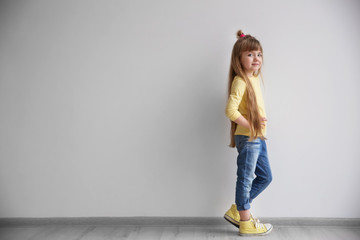 Little fashion girl standing in light room