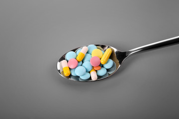 Diet concept. Spoon with pills on color background