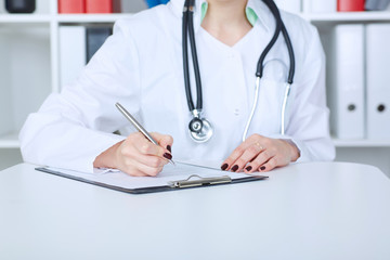 Female doctor filling out medical form while consulting patient