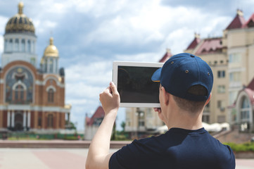 young man on a city street takes pictures of a church