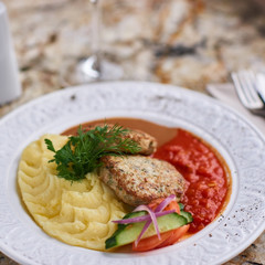 Chicken breast cutlets with mashed potatoes served with mushroom and tomato sauces on white plate on marble table