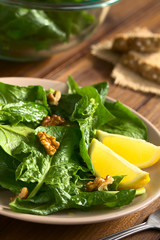 Frischer Spinat und Walnuss Salat mit Zitrone an der Seite, fotografiert mit natürlichem Licht (Selektiver Fokus, Fokus ein Drittel in den Salat) © Ildi