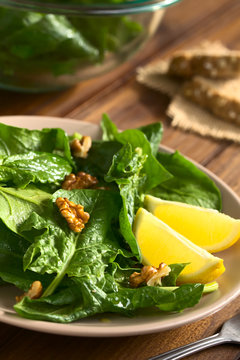Frischer Spinat und Walnuss Salat mit Zitrone an der Seite, fotografiert mit natürlichem Licht (Selektiver Fokus, Fokus ein Drittel in den Salat)