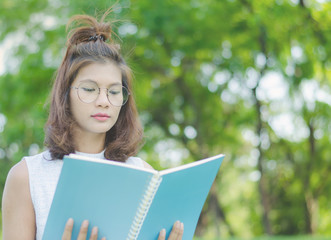 Asian girl reading book at park in summer sunset light. asian woman reading book in Thailand. asian Beautiful woman reading a book in the nature