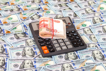 Folded stack of russian roubles and calculator on dollars background