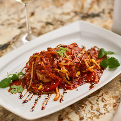 Spicy tofu served on white plate with glass of white wine on marble table. Vegeterian cuisine.