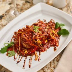 Spicy tofu served on white plate with glass of white wine on marble table. Vegeterian cuisine.
