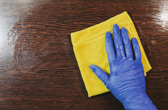 Closeup on woman's hands in blue protective rubber gloves cleaning kitchen cabinets. Instagram