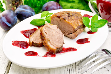 Duck breast with plum sauce in plate on light board