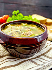 Soup with meatballs and mushrooms in pottery on dark board
