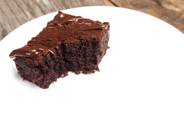 Homemade brownies on white plate. With chocolate fudge topping. Over wooden background. 