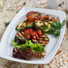 Grilled vegetables served on white plate. Eggplant, tomato, paprika and Zucchini slices.