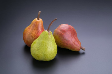 Ripe green and red pears on a black background