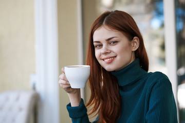 young woman drinks coffee, green jacket